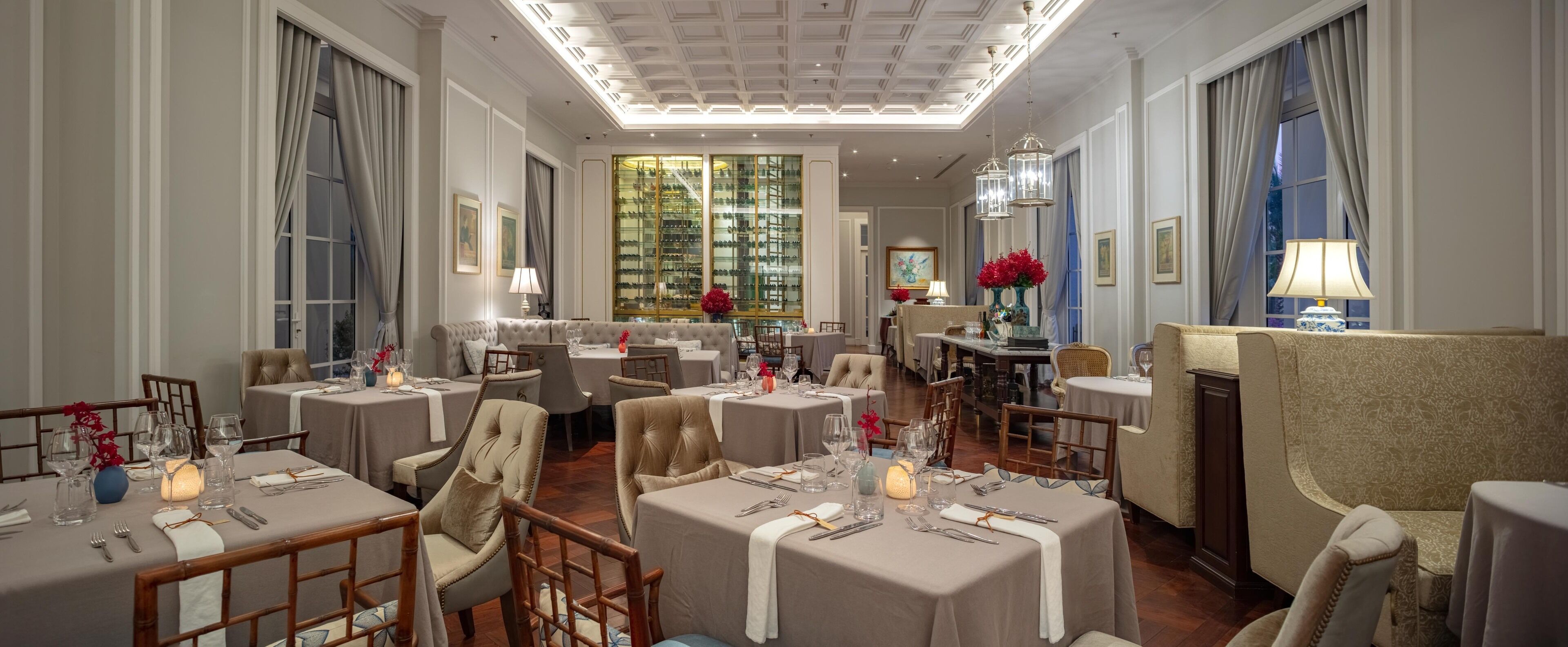 A formal dining room with multiple tables, chairs, and a chandelier.