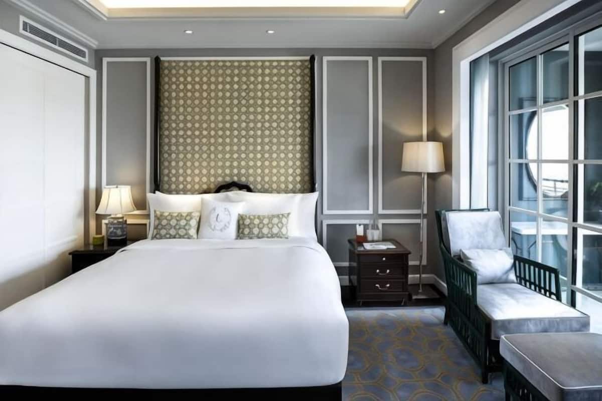 Une chambre dâhĂŽtel avec un grand lit, des tables de chevet, une chaise, une fenĂȘtre et une vue sur lâextĂ©rieur.