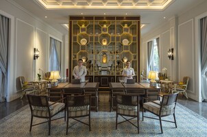 A spacious dining area with a central table, surrounded by chairs, and a decorative wall with shelves.