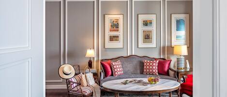 Une pièce avec une table ronde, un canapé et une chaise. Des tableaux encadrés ornent le mur.