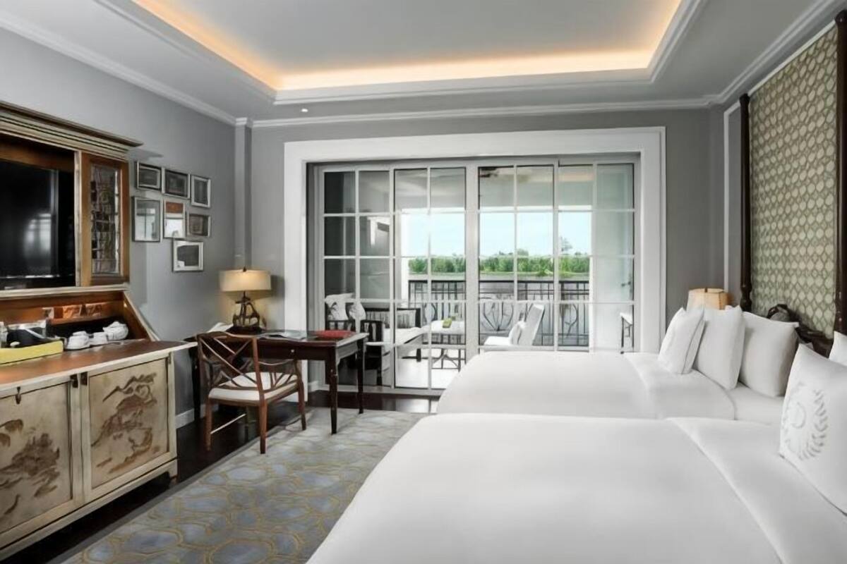Une chambre d’hôtel avec un grand lit, un bureau avec une chaise, une télévision et un balcon avec vue.