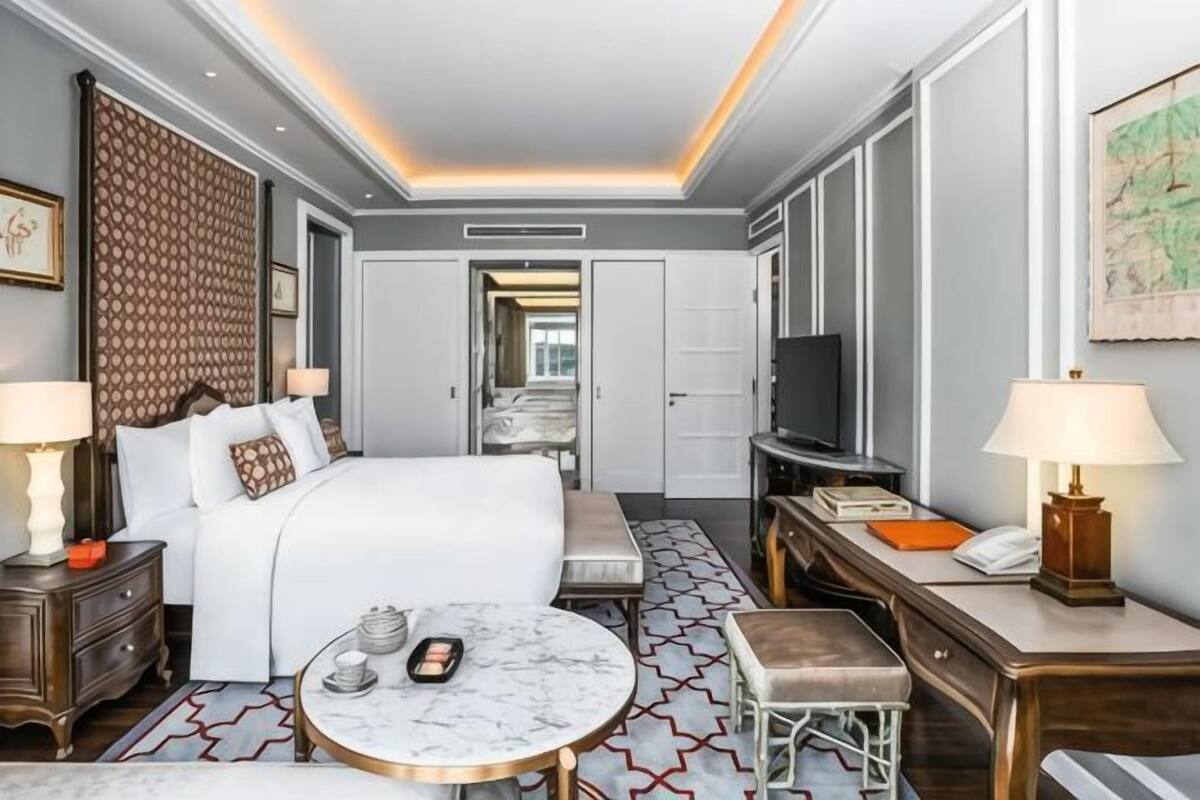 Une chambre d’hôtel comprenant un lit, des tables de chevet, une table ronde, un téléviseur et un miroir.
