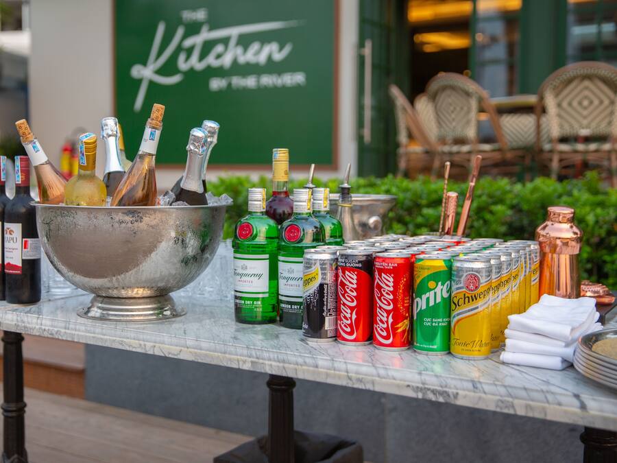 A table with various bottles and cans, including wine, gin, and soda, in an outdoor setting.