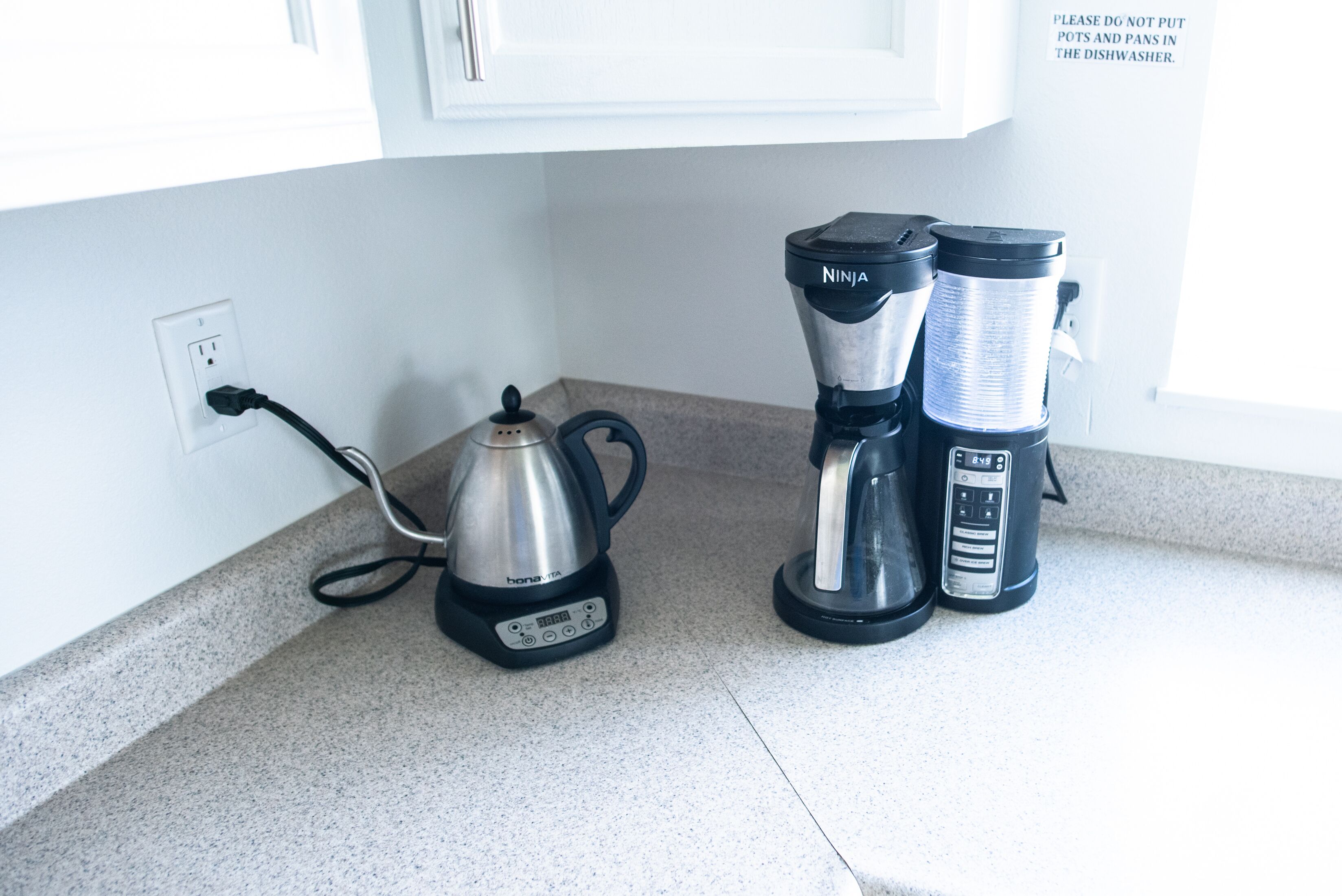 En køkkenbordplade med kaffemaskine, elkedel og blender.