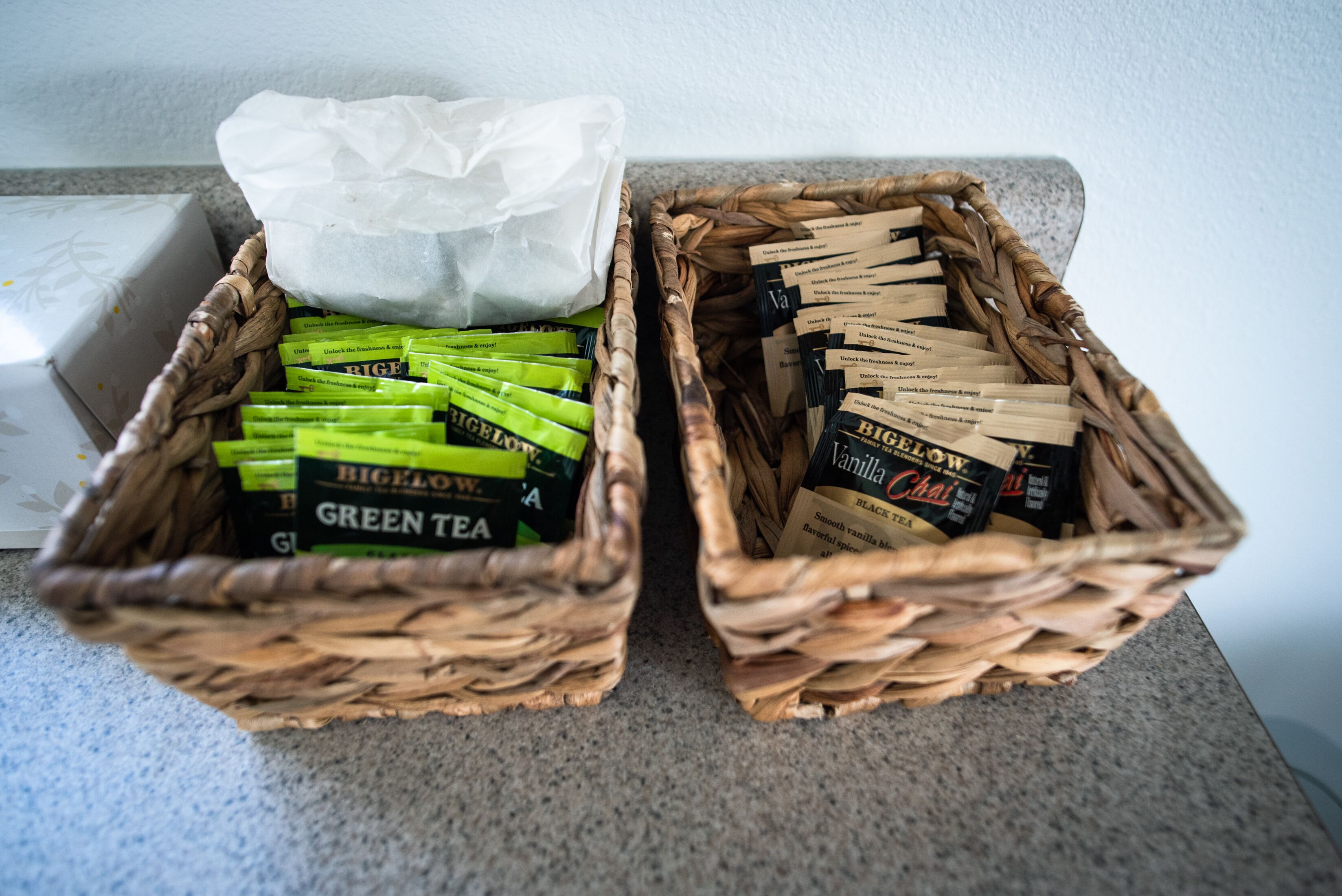 Dos cestas de mimbre con bolsitas de té y una caja de pañuelos.