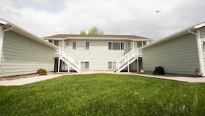 A two-story building with a central staircase and a small lawn area.