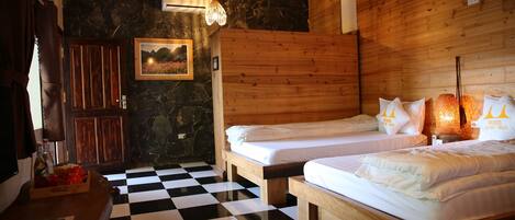 A room with two wooden beds, a checkered floor, a stone wall, and a wooden ceiling.