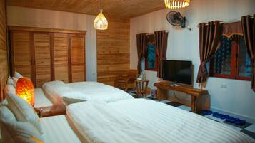A room with two beds, a TV, a fan, and a wooden ceiling.