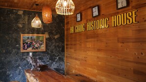 A wooden interior with a reception desk, hanging wicker lamps, and a wall-mounted clock. - Historic Eco House & Ha Giang Loop (Ha Giang 2)