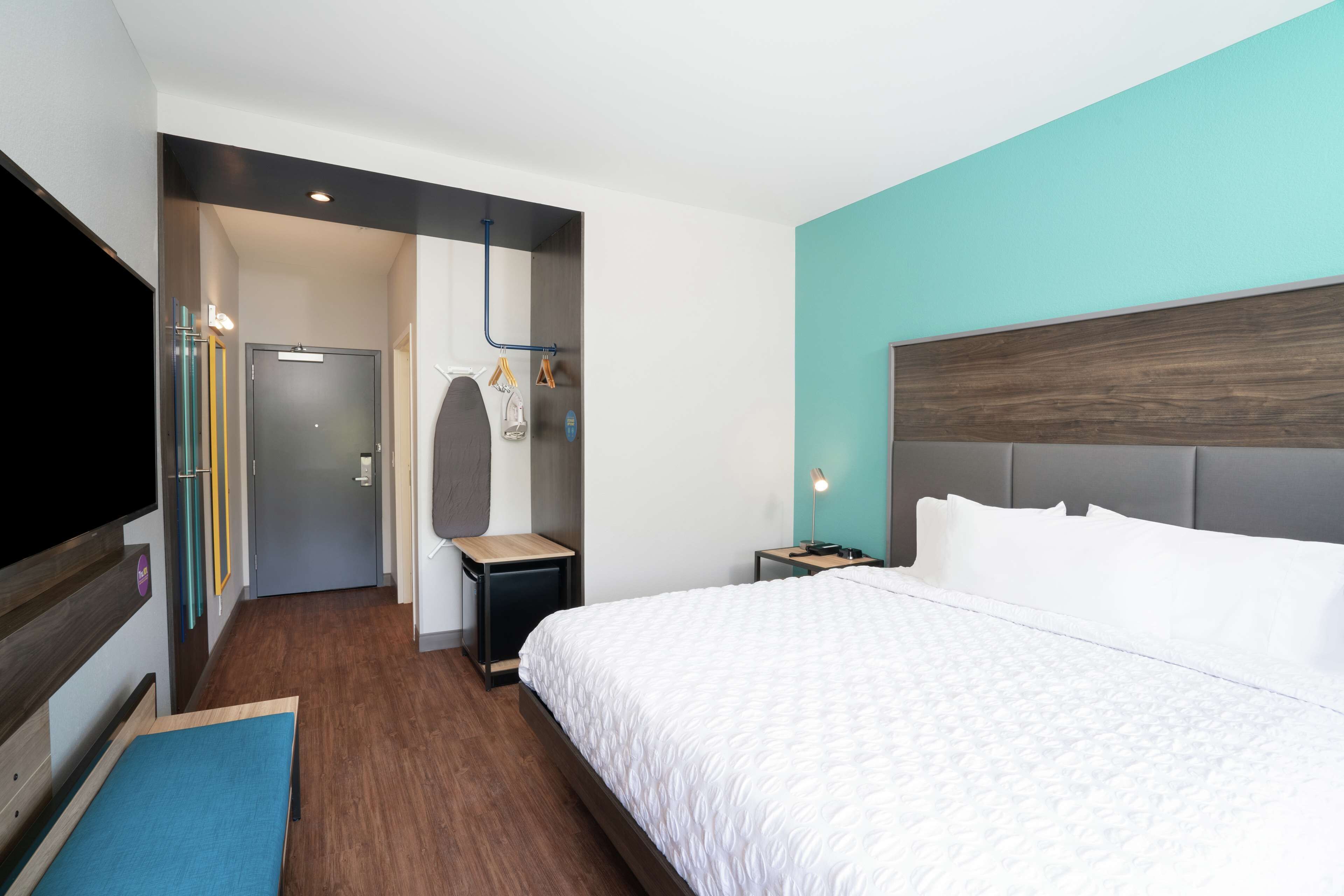 Una habitació d'hotel amb un llit gran, televisió, escriptori i armari.