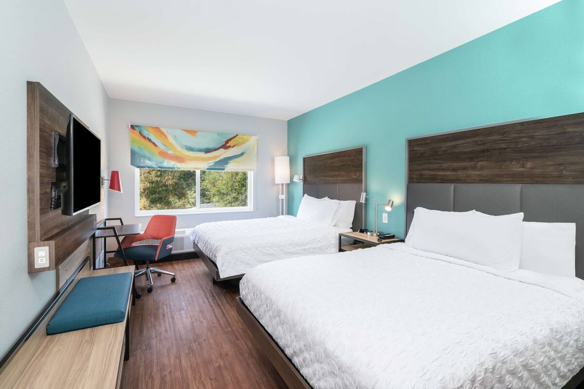 Una habitación de hotel con dos camas, un televisor, un escritorio y una silla.