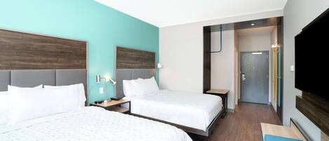 A hotel room with two beds, a TV, and a desk.