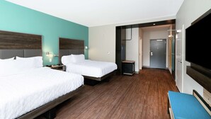 Une chambre d’hôtel avec deux lits, une télévision et un petit bureau.
