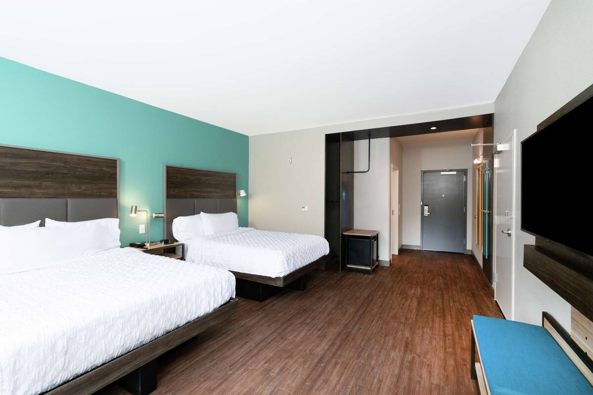 A hotel room with two beds, a TV, and a small desk.