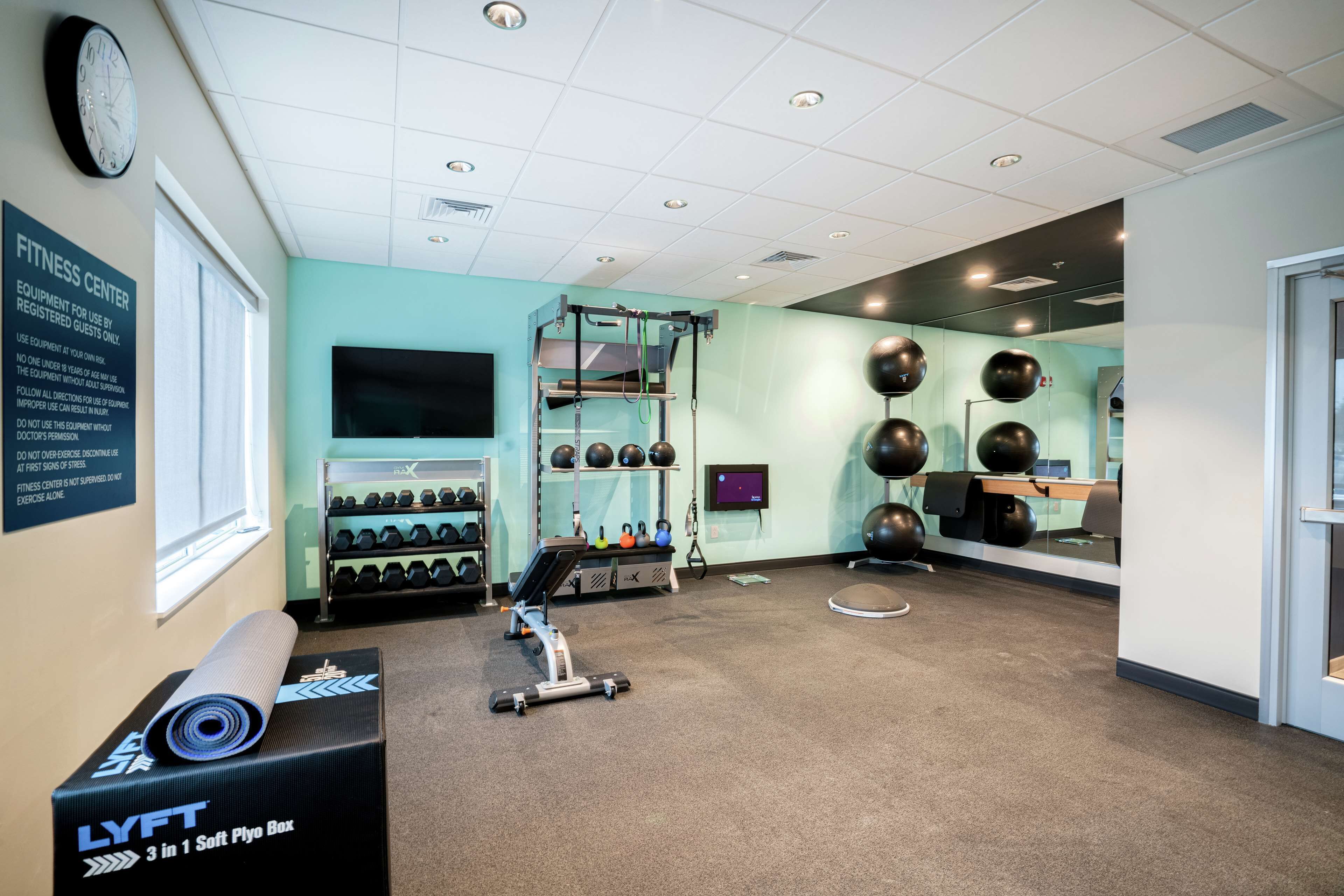 A fitness center with a treadmill, weight machines, and exercise balls.