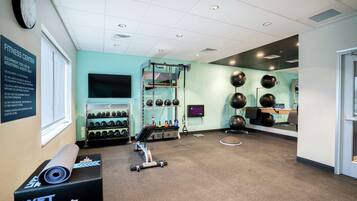 A fitness center with a treadmill, weight machines, and exercise balls.