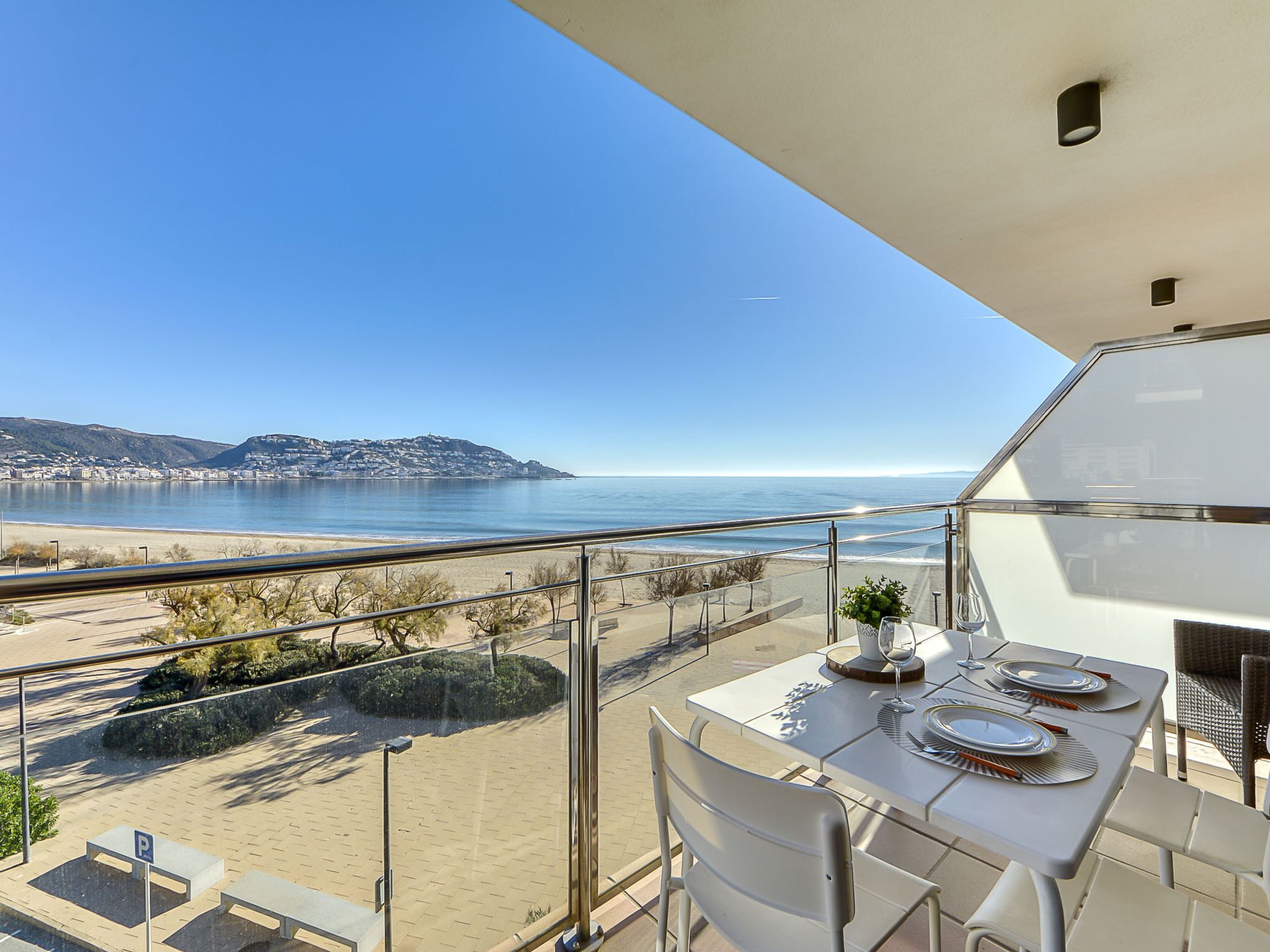 Een balkon met een eettafel, met uitzicht op een strand en de zee.