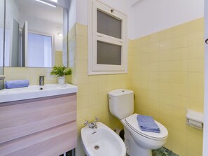 Une salle de bain équipée d’un lavabo, d’un bidet, de toilettes et d’un miroir.