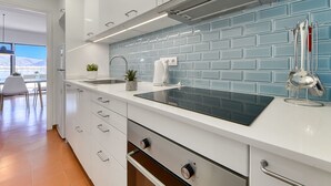 A modern kitchen with white cabinets, a blue tiled backsplash, stainless steel appliances, and a view of the outdoors. - Apartment Rhodas by Interhome (Roses)