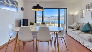 A modern living room with a dining area, large windows with a sea view, and a sofa with decorative pillows. - Apartment Rhodas by Interhome (Roses)