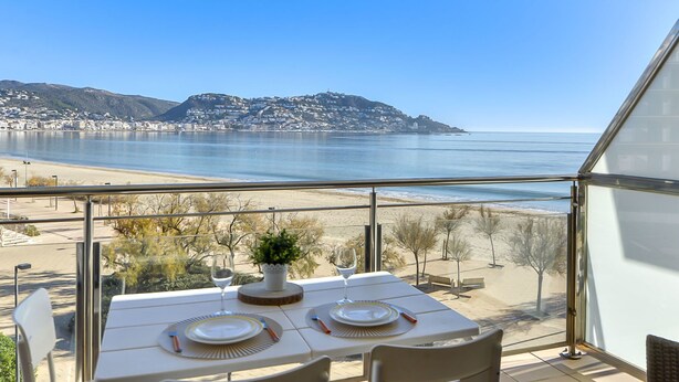 A table set for two with a view of the sea and a distant hill. - Apartment Rhodas by Interhome (Roses)