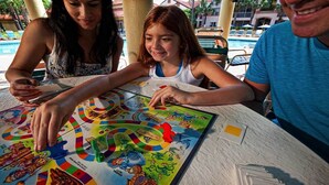 A group of people playing a board game at a table by a poolside. - Cozy Two Bedroom Resort Condo Very close to DISNEY (Orlando)