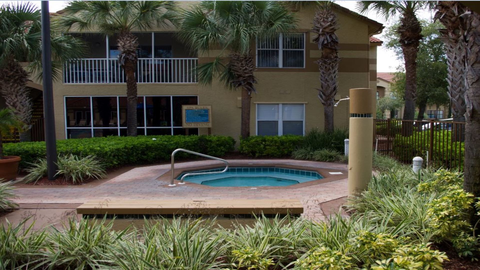 A pool area with a hot tub, surrounded by palm trees and a building with a sign that reads "No Diving."