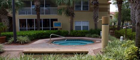 A pool area with a hot tub, surrounded by palm trees and a building with a sign that reads "No Diving."