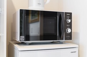 A microwave oven with a digital display and control panel, placed on a white countertop.