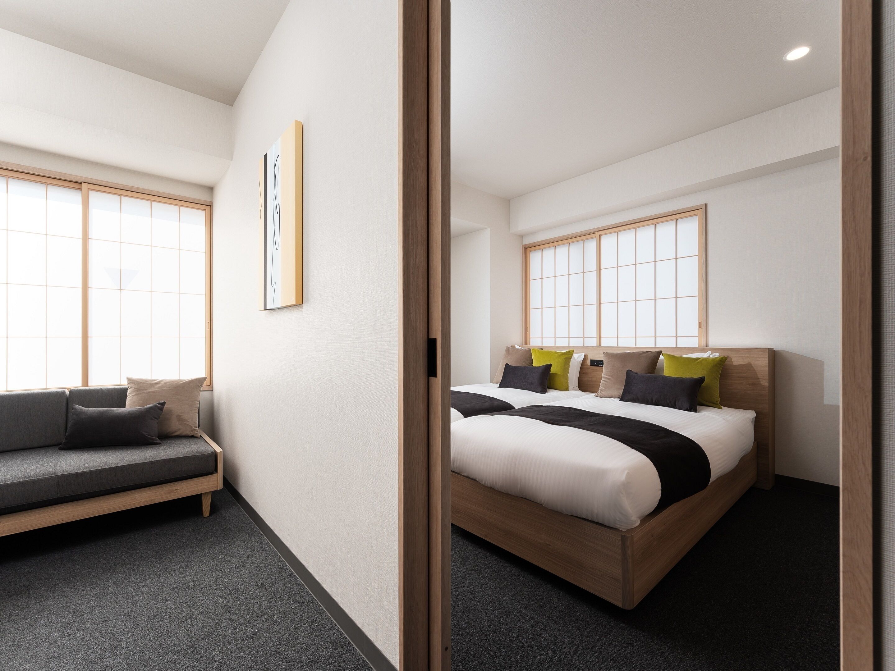 Une chambre d’hôtel moderne avec un lit, un canapé et de grandes fenêtres.