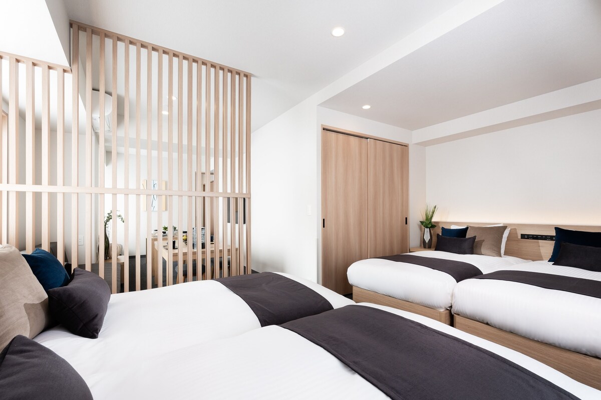 A modern hotel room with a large bed, a desk, and a sliding door.
