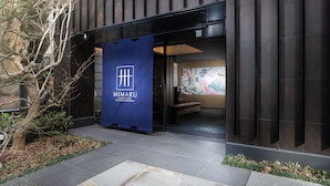 Fachada del Mimaru Apartment Hotel con un cartel azul que muestra el nombre del hotel.