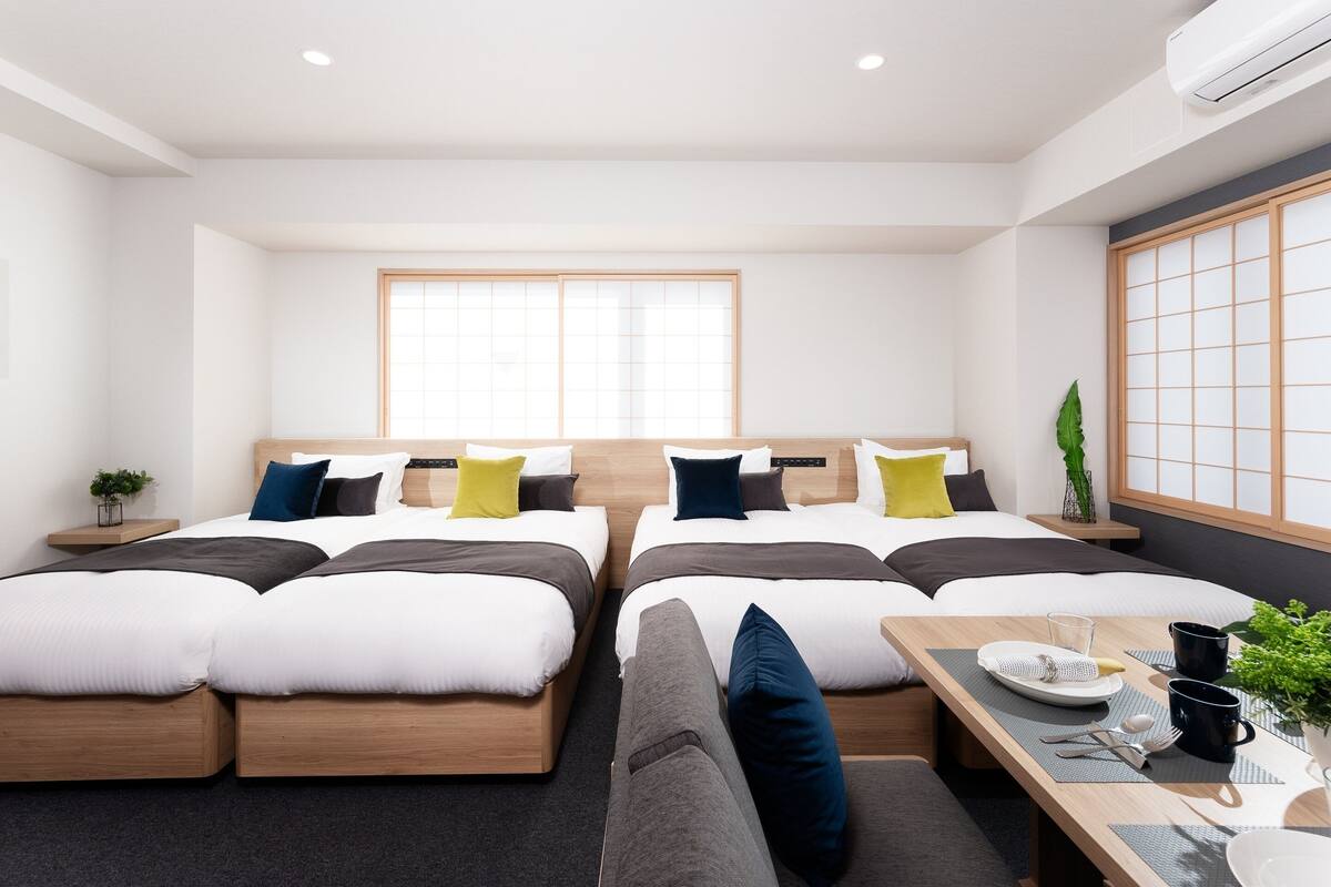 Une chambre d’hôtel moderne avec deux lits, une table à manger et une grande fenêtre.