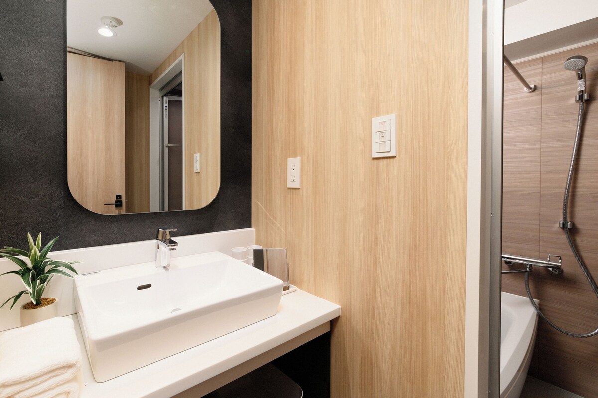 A modern bathroom with a white sink, a mirror, and a shower.