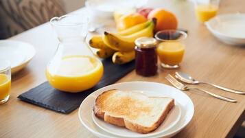 A breakfast setting with toast, fruit, and orange juice on a wooden table.
