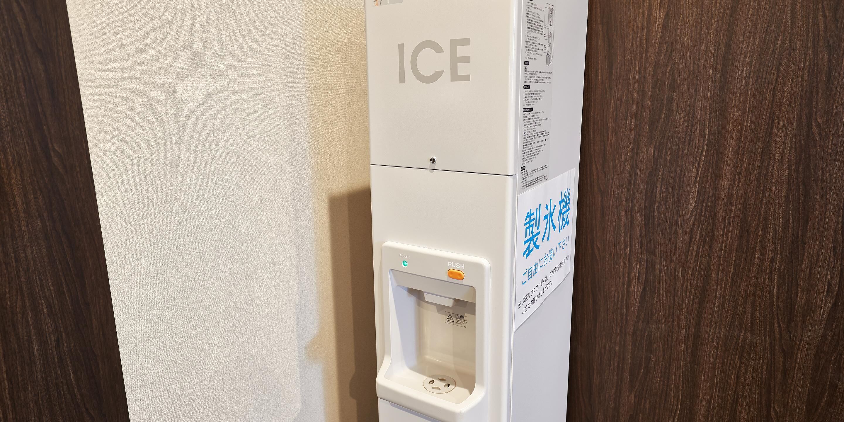 Un distributeur de glaçons blanc, doté d’un bouton-poussoir et d’une étiquette d’avertissement.