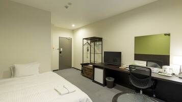 A hotel room with a bed, desk, chair, and a small table with a glass top.