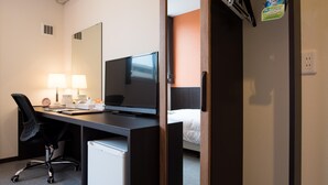 A hotel room with a desk, chair, television, bedside table, lamp, and a bed. - Crown Hotel Okinawa Annex (Okinawa)