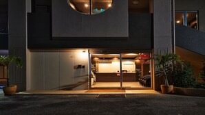 A modern hotel entrance with a reception desk, a staircase, and potted plants. - Crown Hotel Okinawa Annex (Okinawa)