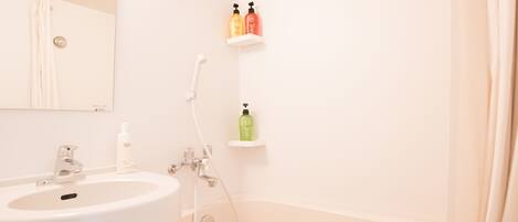 A bathroom with a sink, mirror, shower, and two shelves with toiletries.