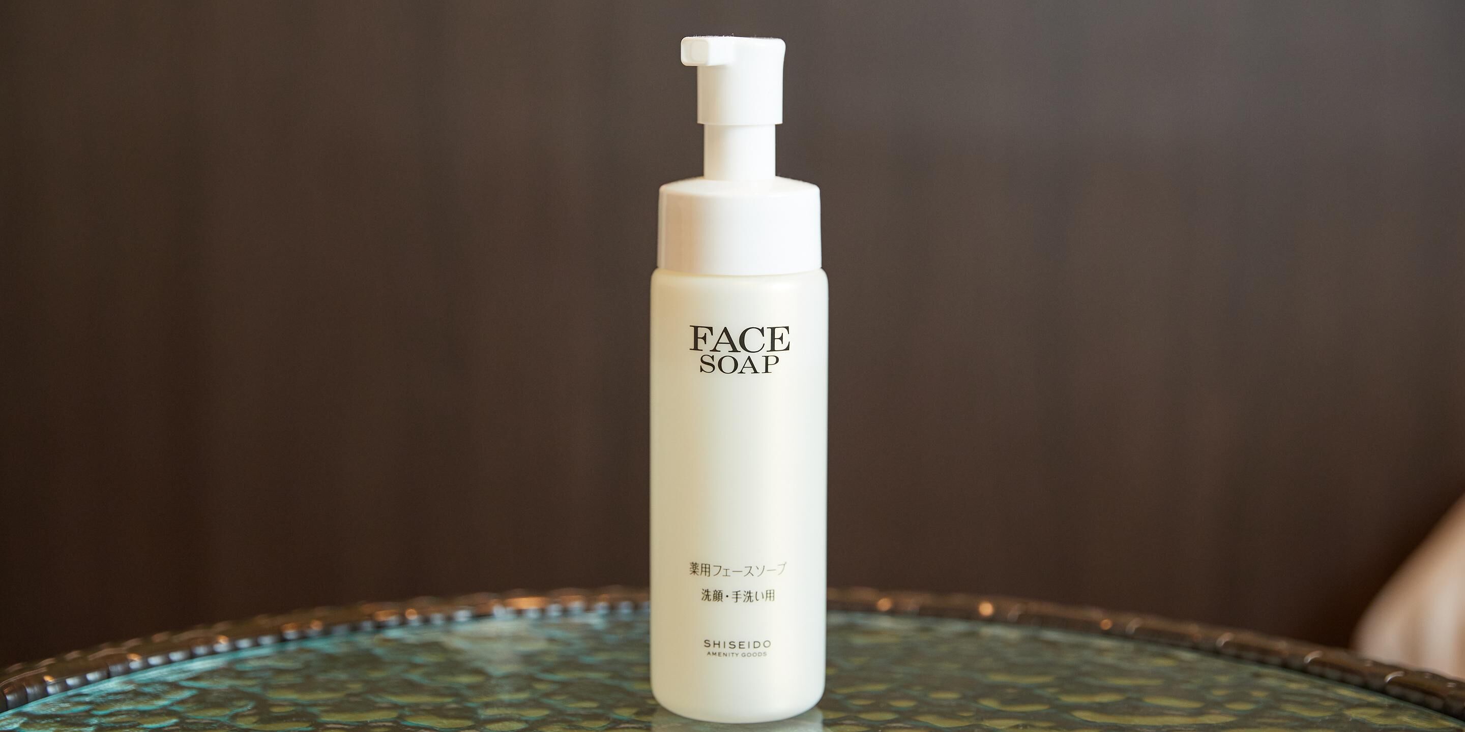 A bottle of face soap on a glass table.