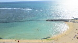 A beach with clear turquoise water, a sandy shore, and a rocky breakwater. - Crown Hotel Okinawa Annex (Okinawa)
