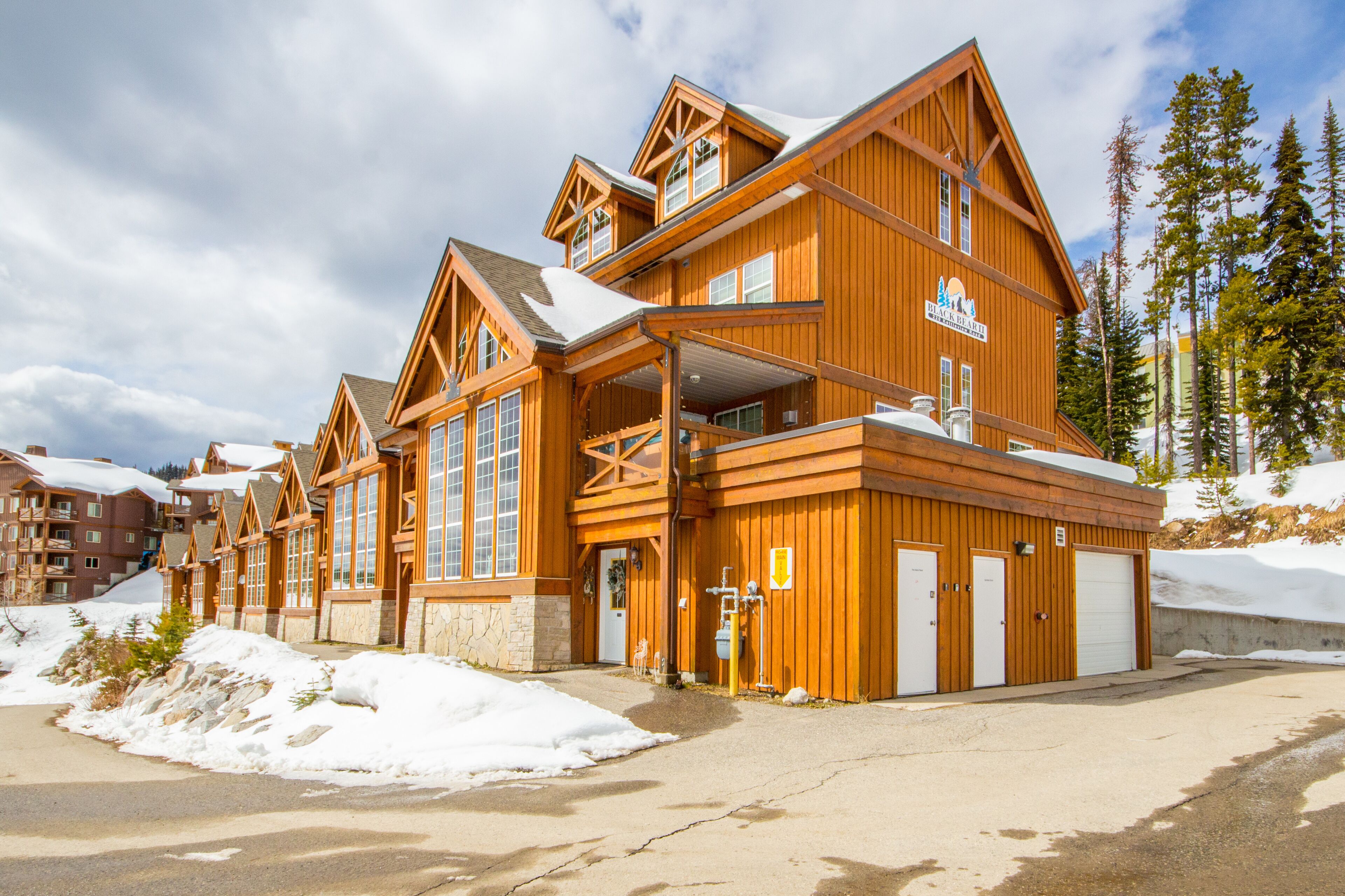 A wooden lodge with multiple floors, large windows, and a covered outdoor area.