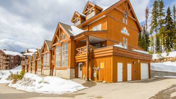 A wooden lodge with multiple floors, large windows, and a covered outdoor area.