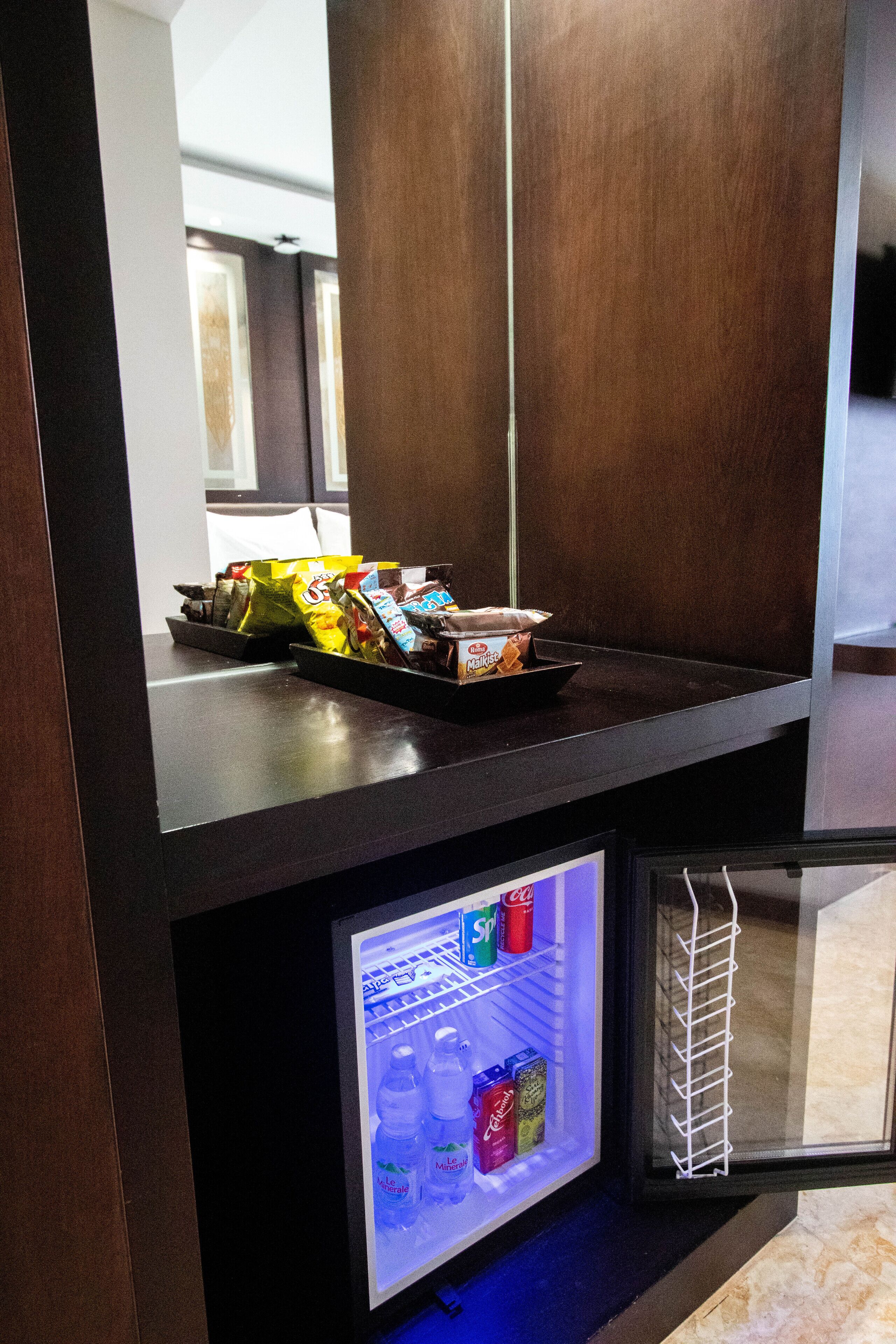 Un mini-bar avec des en-cas et un réfrigérateur rempli de boissons.