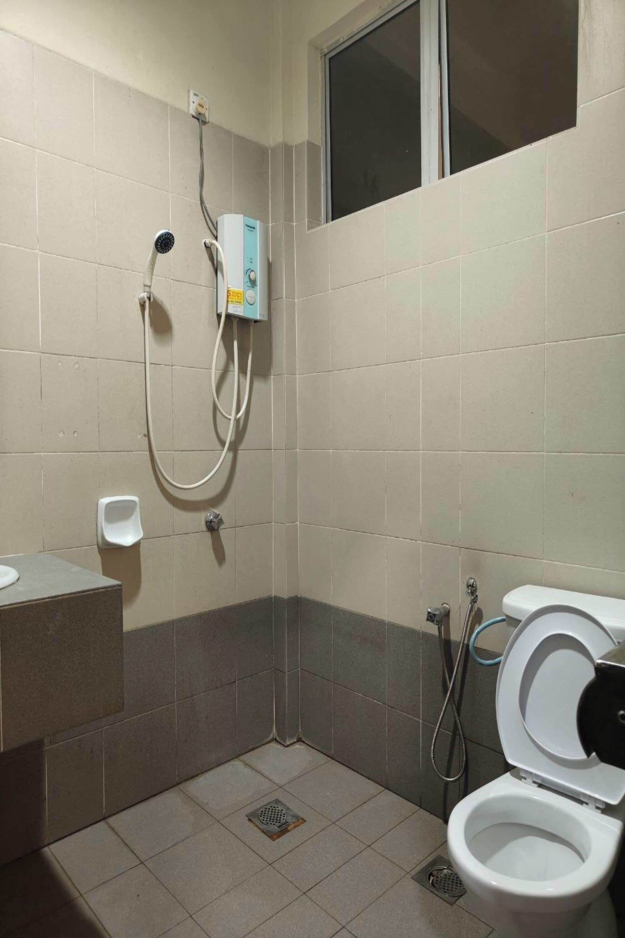 Un baño pequeño con azulejos, un inodoro, ducha y dispensador de jabón.