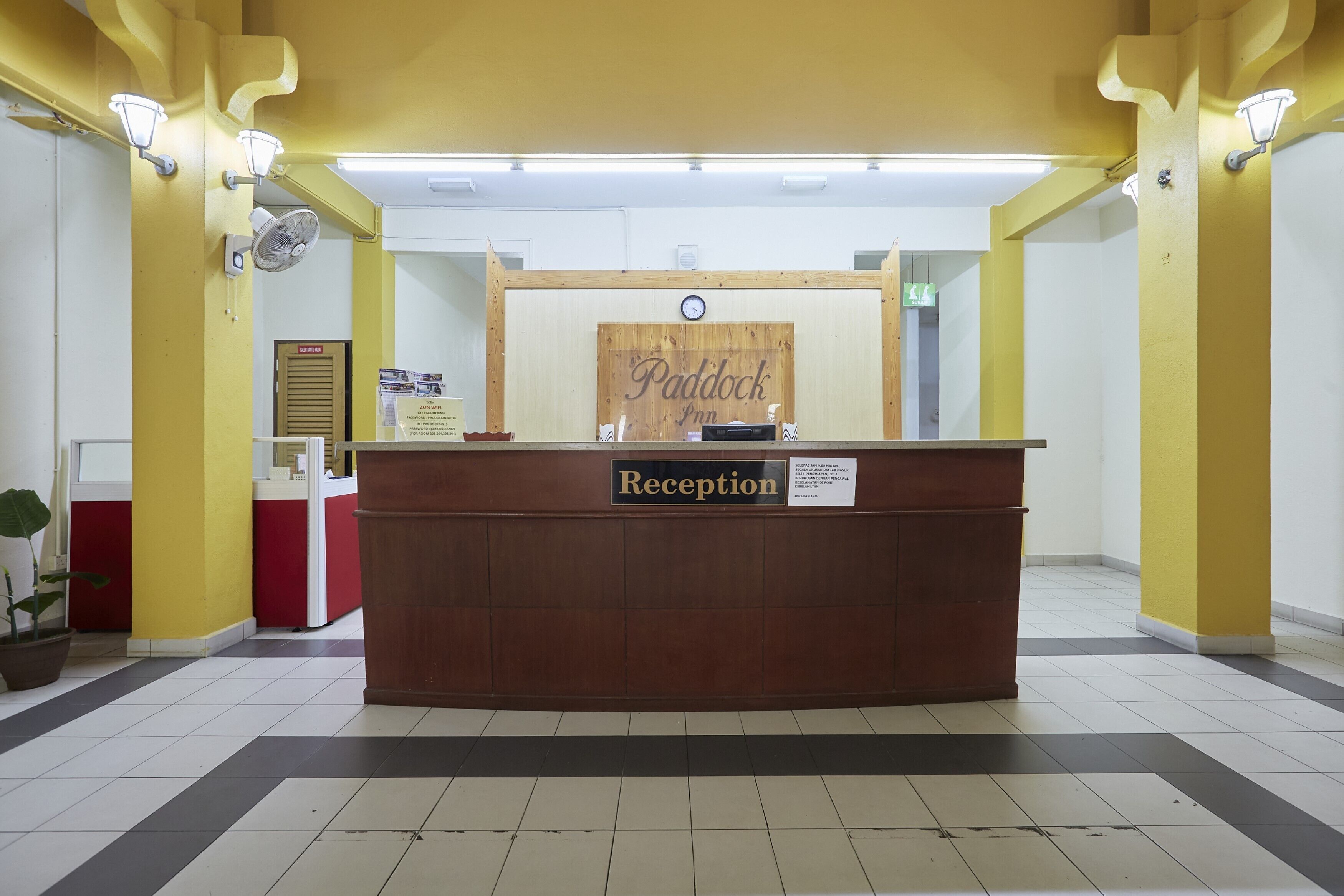 A reception desk with a sign reading "Paddock Inn Reception" and a clock above it.