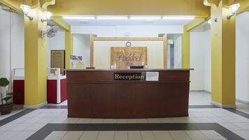 A reception desk with a sign reading "Paddock Inn Reception" and a clock above it.