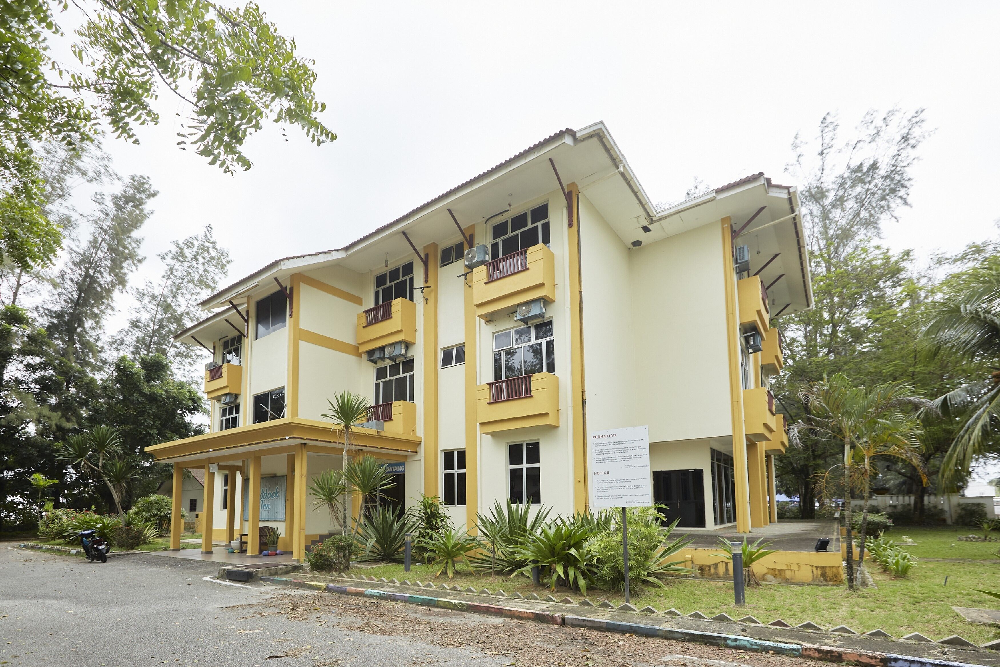 A multi-story building with a yellow facade, multiple balconies, and a covered entrance area.
