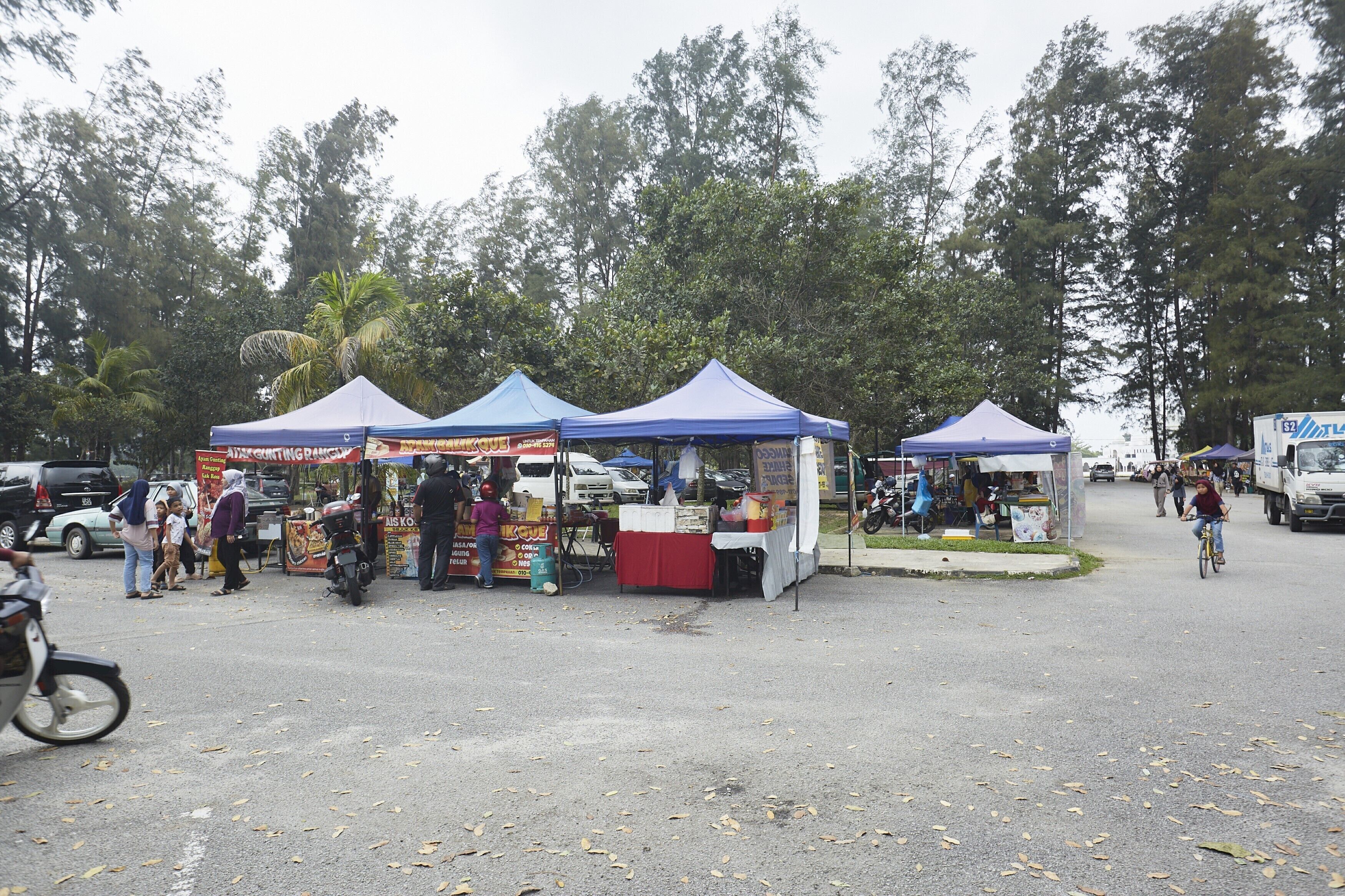 A street market with several food stalls under blue and white tents.